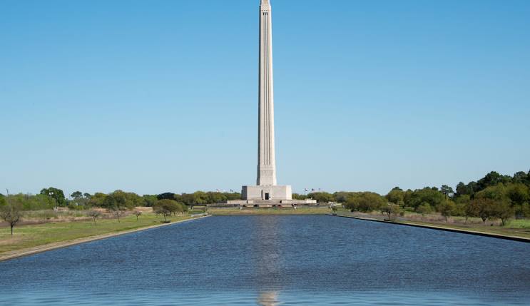 Monument reflecting in water with green landscape, symbolizing heritage and history in Harris County, TX.