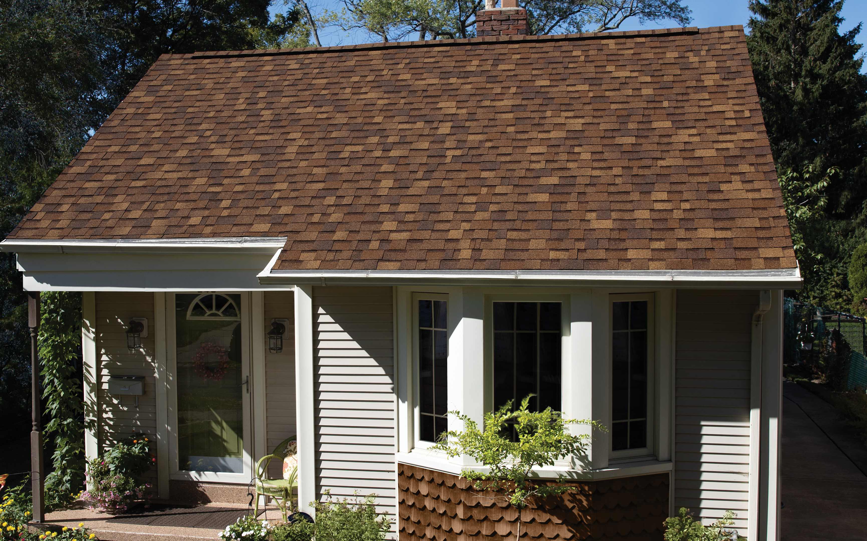 Roofing shingles in Desert Rose color on a residential home, showcasing dimensional aesthetics and Class 4 impact resistance, complemented by a well-maintained exterior and landscaping.